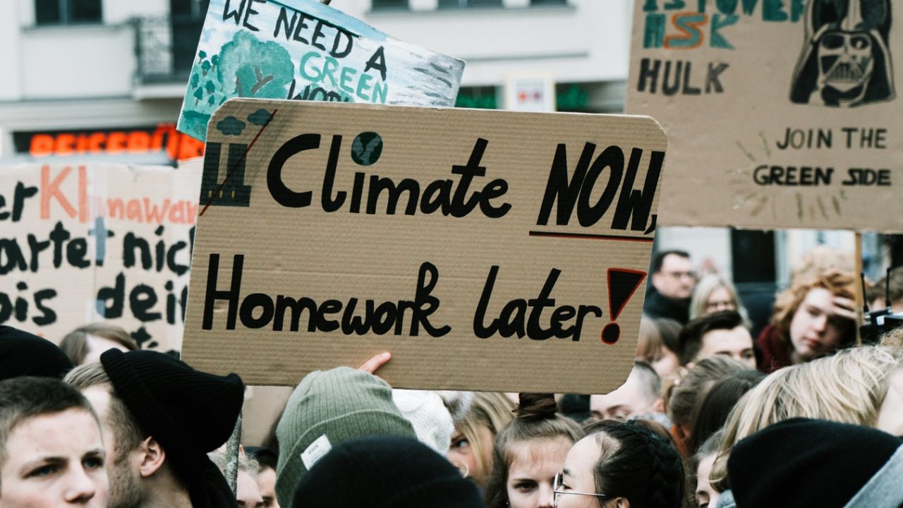 Sign that reads "climate now homework later" at a climate strike